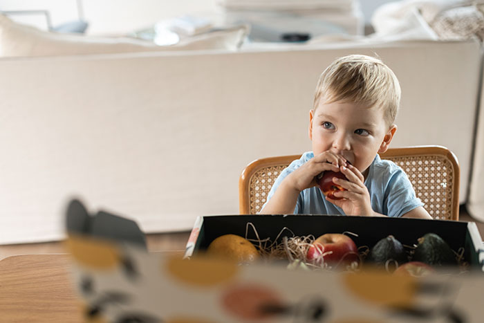 Child eating apple from gift box